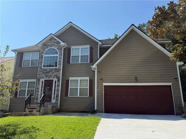 Two-story residence featuring a stone facade accent, arched transom window, covered entry, and attached two-car garage