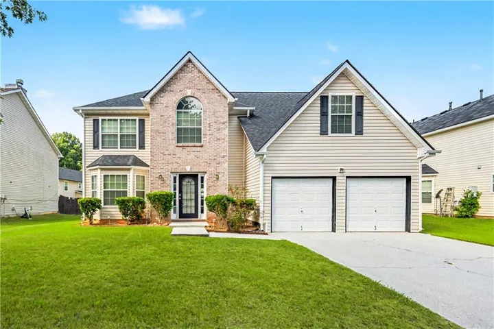 Two-story residence featuring a brick facade with siding accents, an arched window, and a bay window