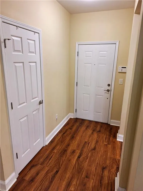 View of hardwood flooring Foyer, with coat closet to left and Kitchen entry to right.