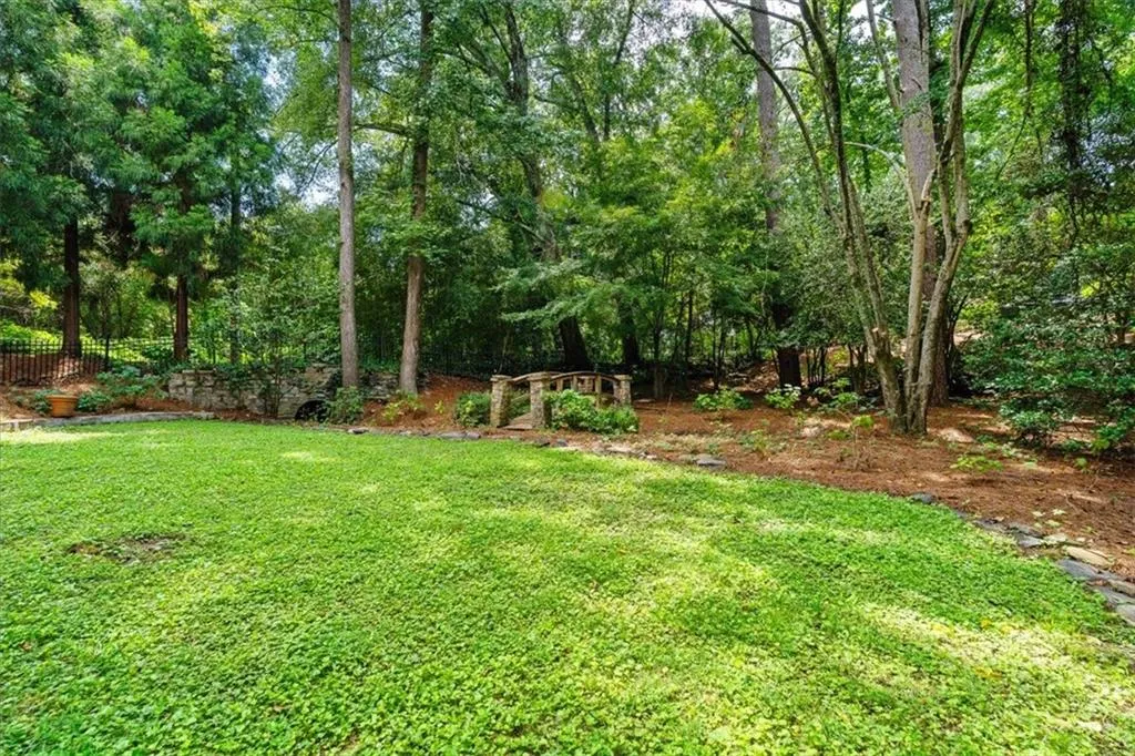 Expansive lawn area with a stone retaining wall and mature trees