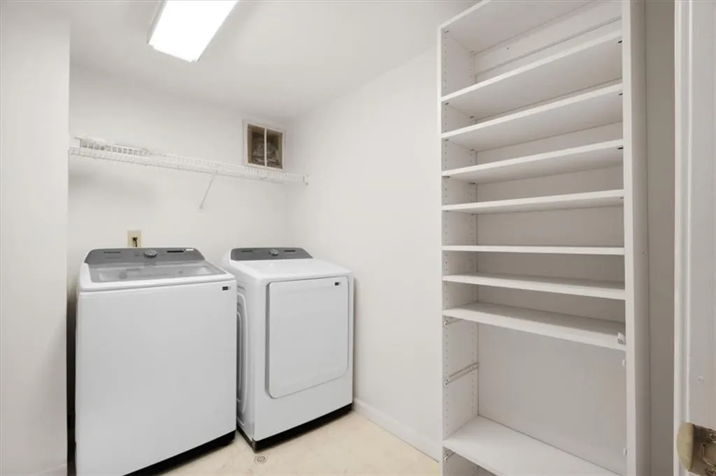 Laundry area with a wire shelf, overhead lighting, included washer and dryer, and built-in shelving unit