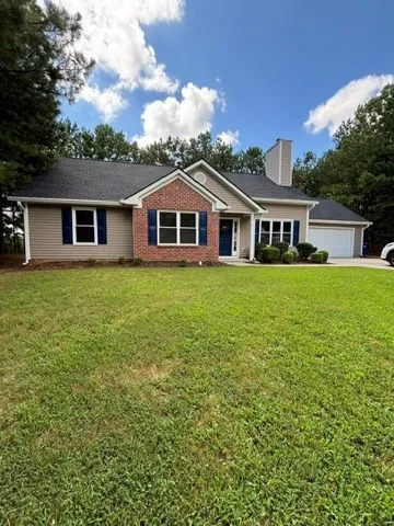 Two-story home with brick and siding exterior, prominent chimney, and attached garage
