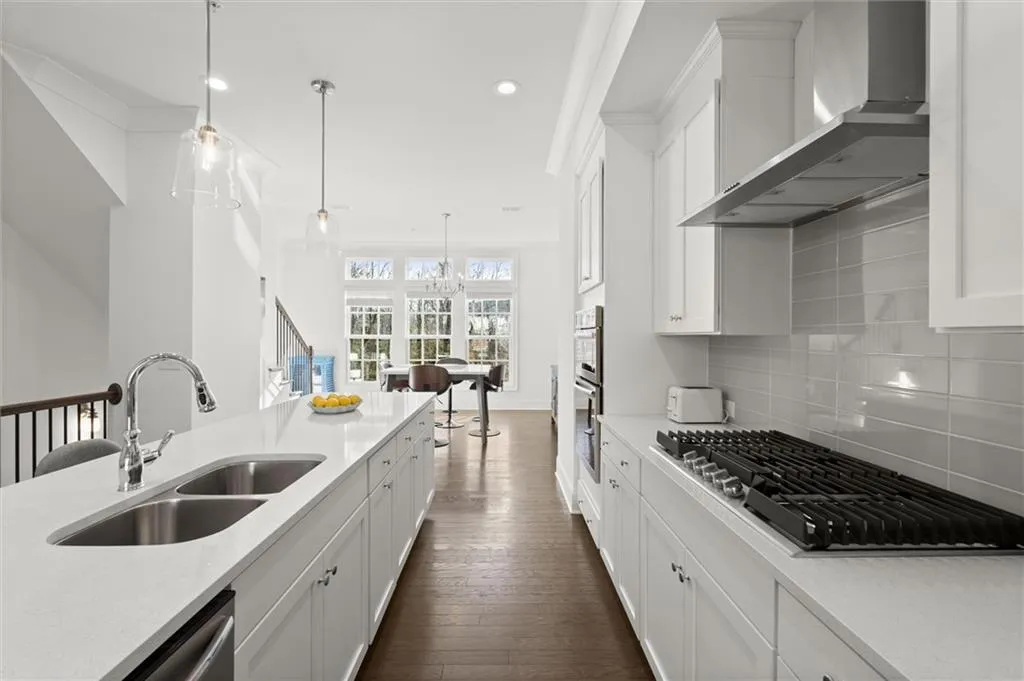 Kitchen featuring white cabinets, wall chimney exhaust hood, appliances with stainless steel finishes, light stone countertops, and recessed lighting