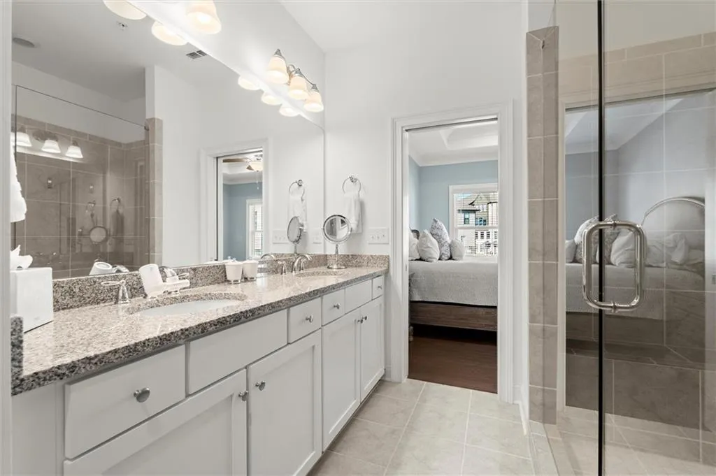 Bathroom with a stall shower, double vanity, connected bathroom, and light tile patterned floors