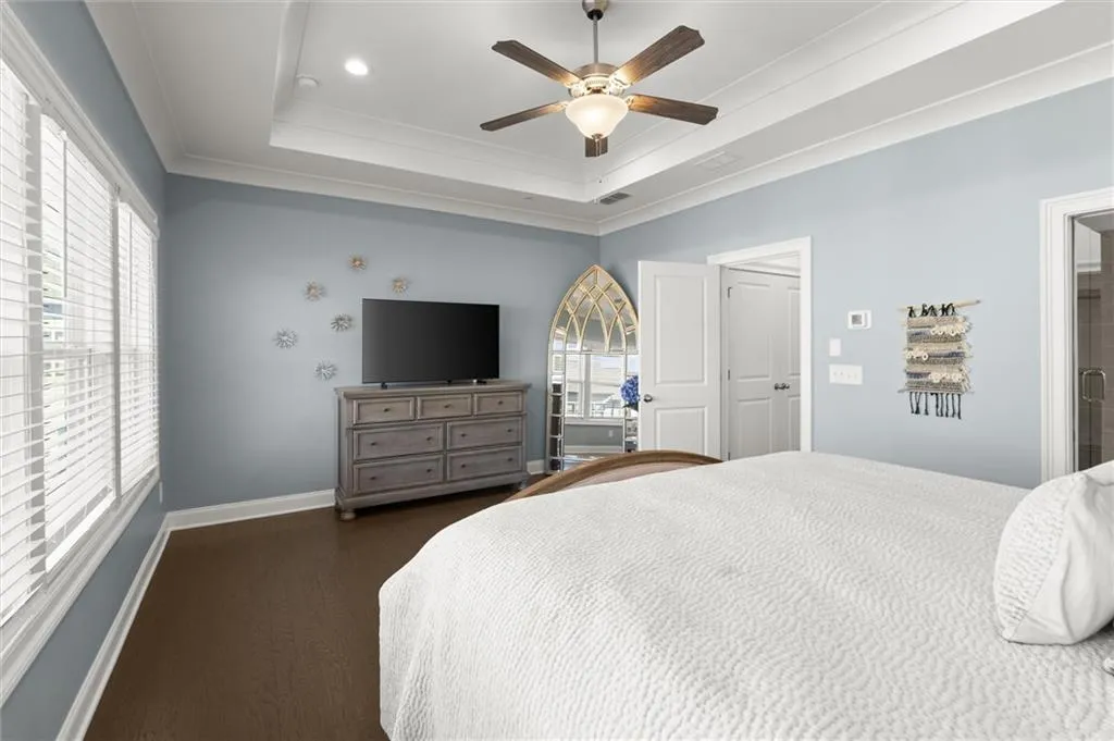 Bedroom featuring ornamental molding, dark wood-type flooring, and a ceiling fan