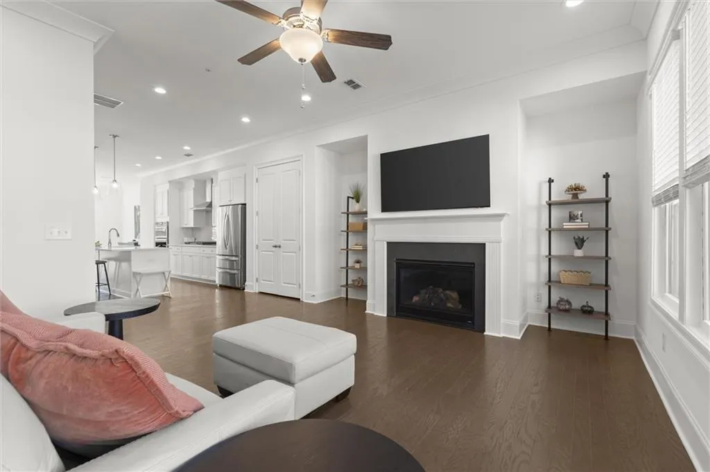 Living area with crown molding, a glass covered fireplace, recessed lighting, dark wood-style floors, and ceiling fan