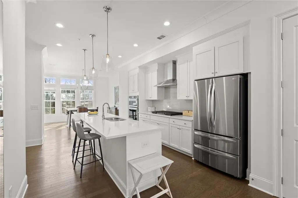 Kitchen with appliances with stainless steel finishes, recessed lighting, white cabinetry, a breakfast bar, and dark wood-type flooring