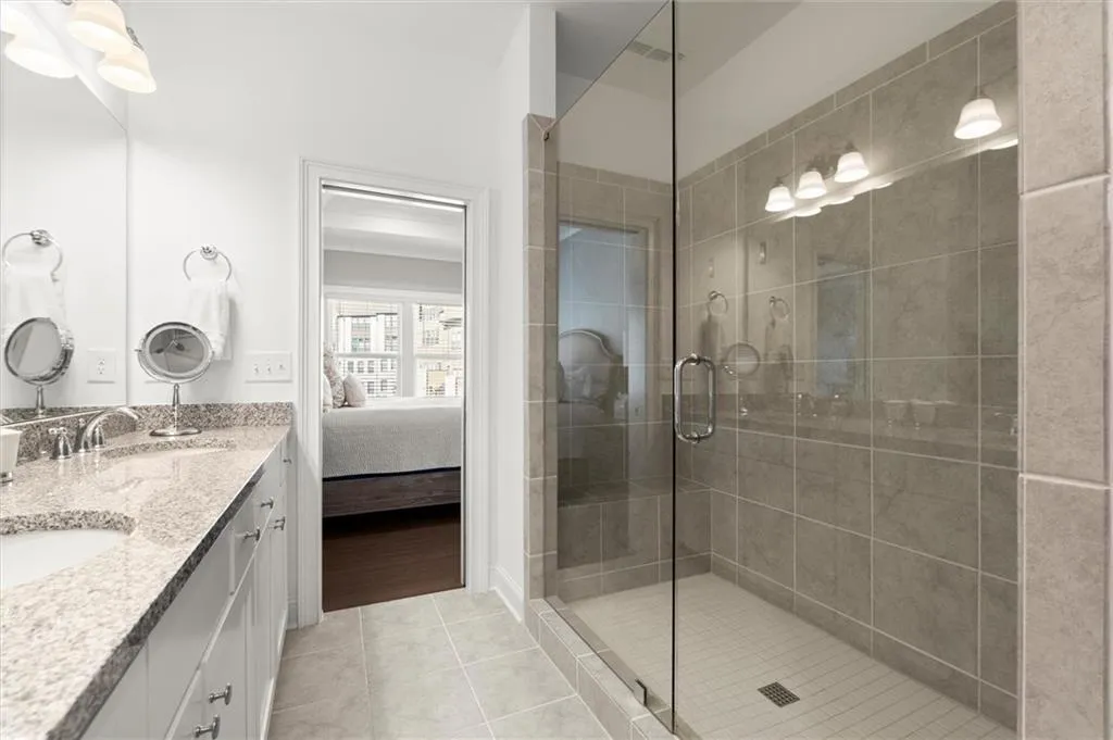 Full bathroom with connected bathroom, double vanity, a shower stall, and light tile patterned floors