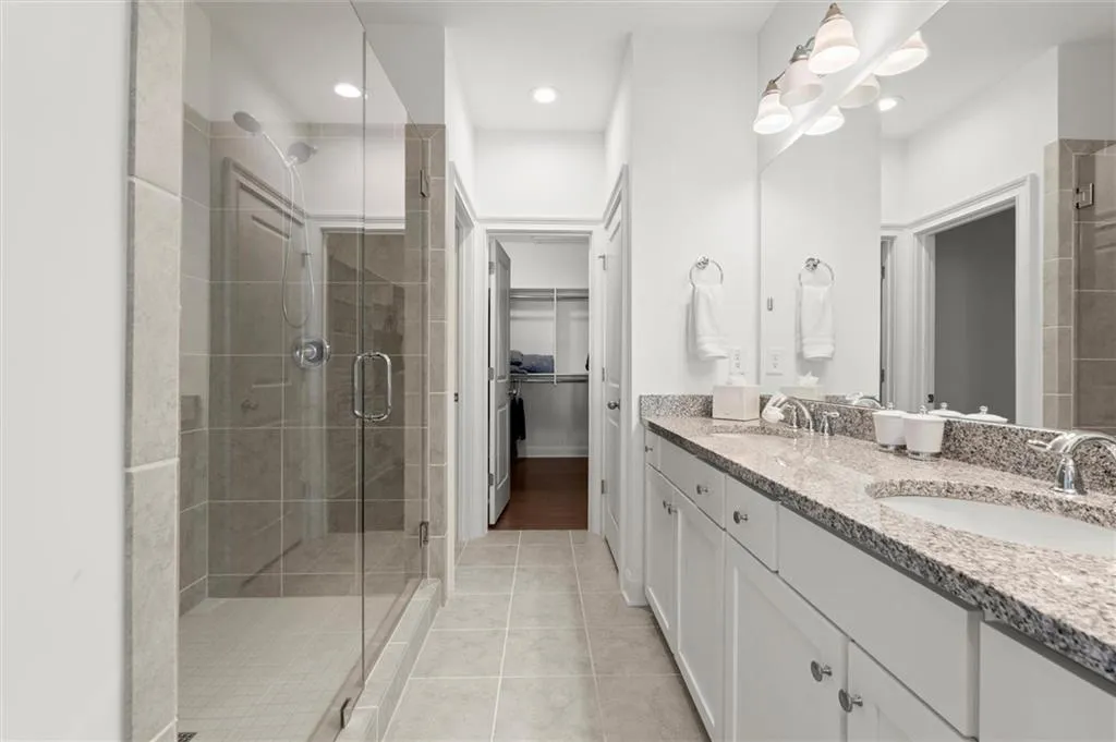 Bathroom with double vanity, a stall shower, a walk in closet, light tile patterned flooring, and recessed lighting