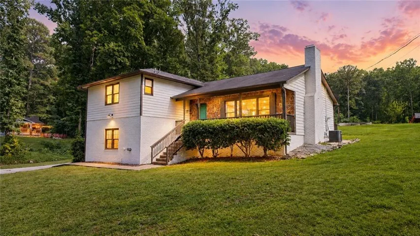 Split-level residence featuring white siding and stone accents