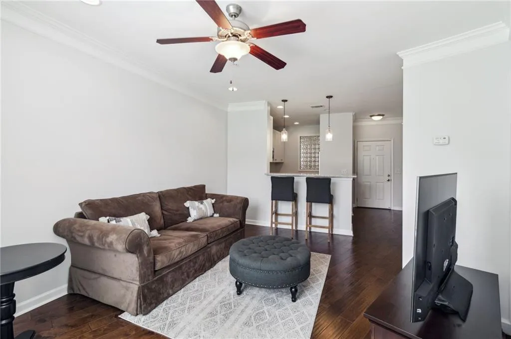 Living room featuring ceiling fan, ornamental molding, dark wood-style flooring, baseboards, and recessed lighting