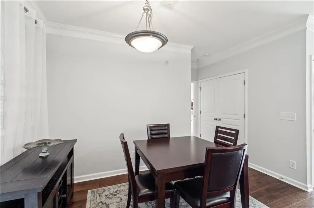 Dining area featuring crown molding, dark wood-style floors, and baseboards