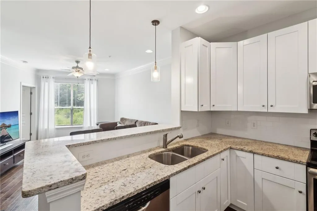 Kitchen with a sink, ornamental molding, white cabinets, a peninsula, and open floor plan