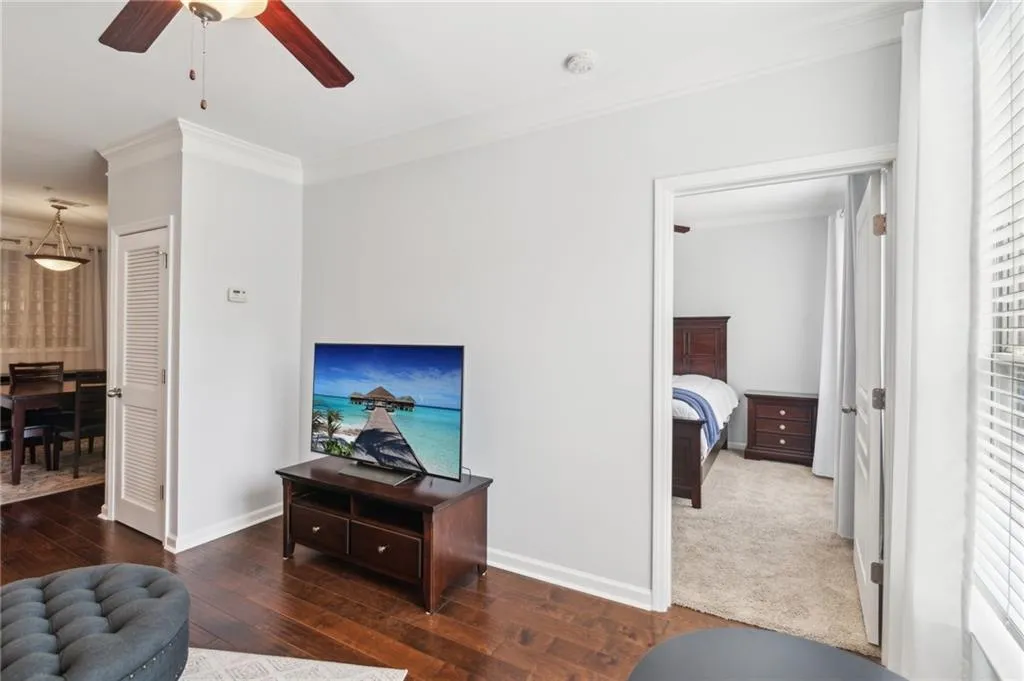Living room with crown molding, baseboards, hardwood / wood-style floors, a ceiling fan, and healthy amount of natural light