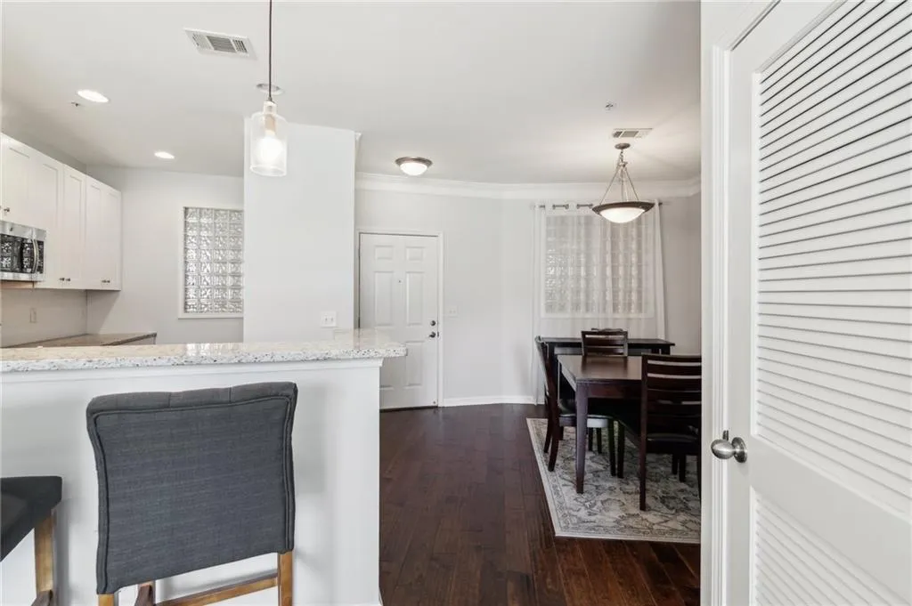 Kitchen featuring stainless steel microwave, dark wood finished floors, white cabinetry, decorative light fixtures, and crown molding