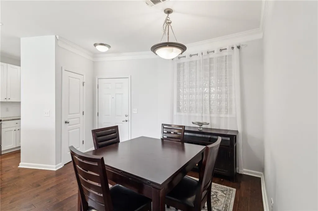Dining space featuring dark wood-type flooring, crown molding, and baseboards