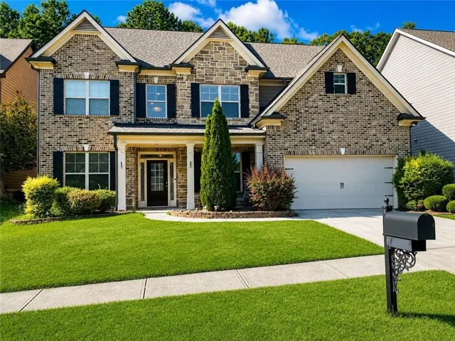 Traditional-style exterior with a brick and stone facade, two-car garage, covered porch entry, and a concrete driveway