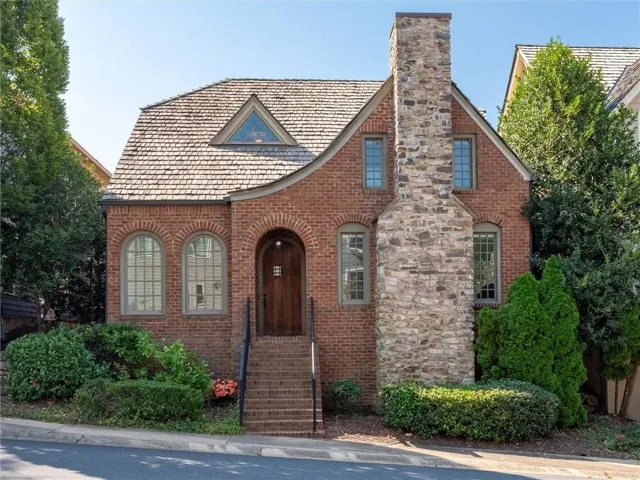 Brick exterior with a stone chimney, arch-top entry, and wood shingle roof