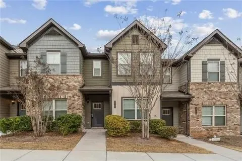 Townhome exterior with a mix of brick and horizontal siding, featuring gabled roofs and individual covered entryways