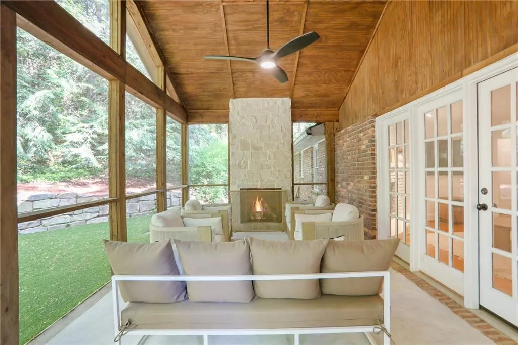 Sunroom featuring french doors, an outdoor living space with a fireplace, and a ceiling fan
