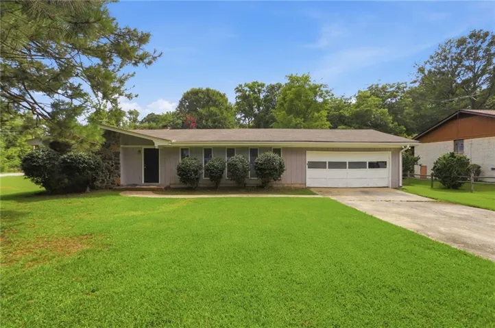 Ranch-style exterior with a light gray facade, attached garage, and a concrete driveway