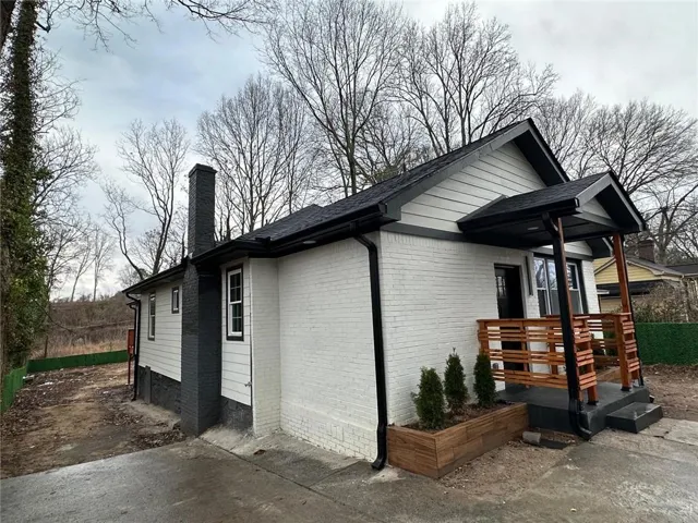 View of home's exterior featuring a porch, a chimney, and brick siding