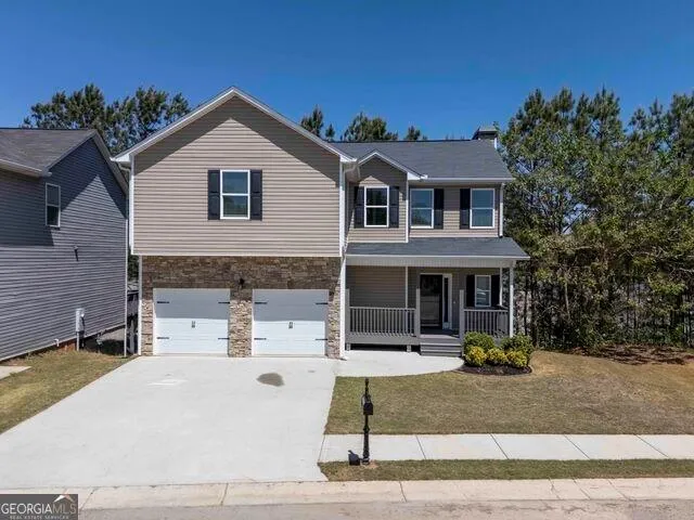 Two-story residence featuring a covered front porch, a two-car garage with stone accents, and a concrete driveway