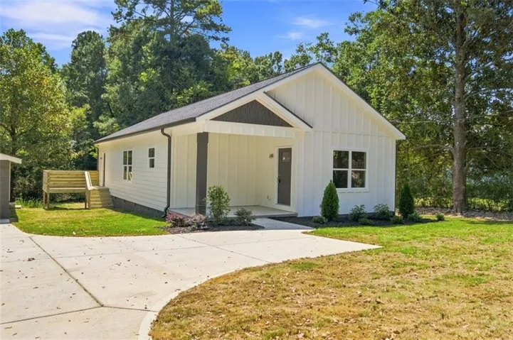 White board-and-batten exterior with contrasting dark trim, covered front porch, and a concrete driveway