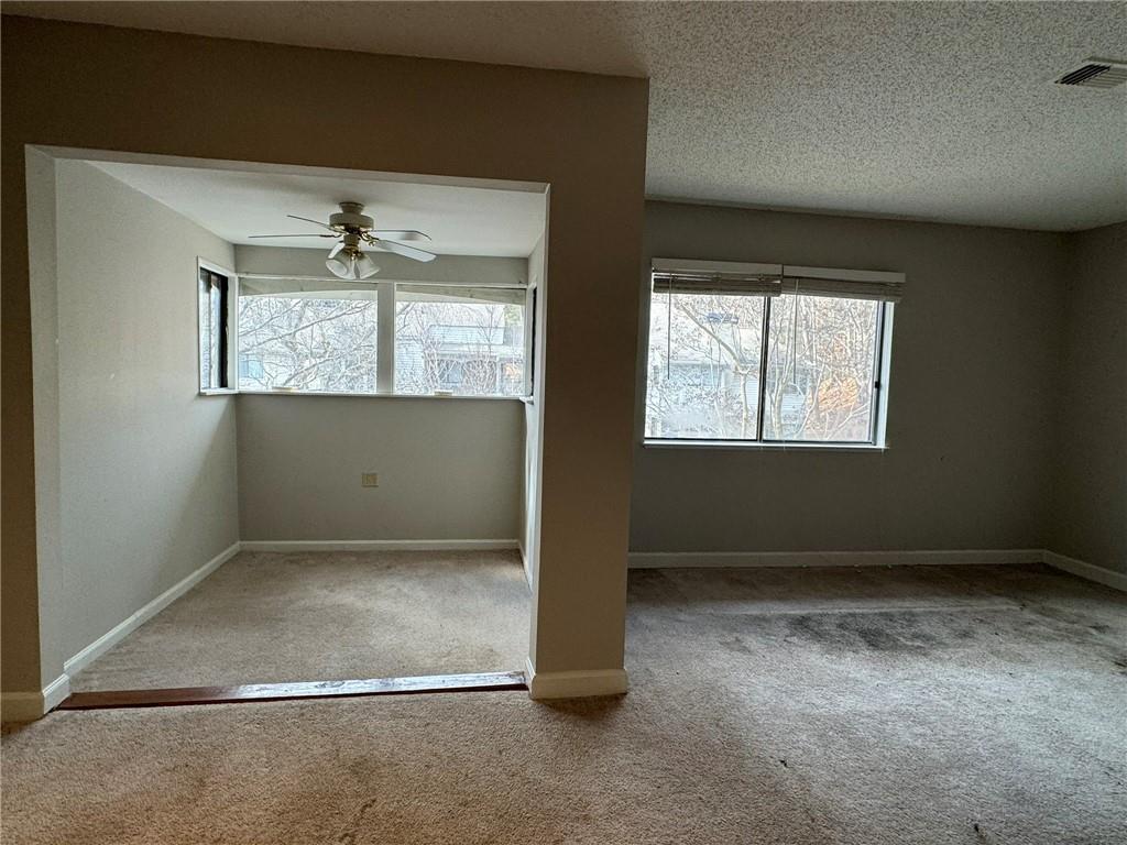 Carpeted empty room featuring a textured ceiling and ceiling fan