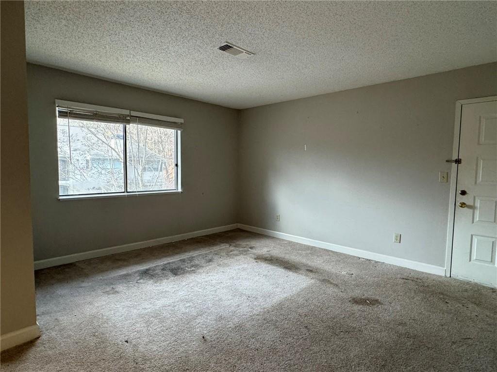 Unfurnished room with a textured ceiling and light carpet