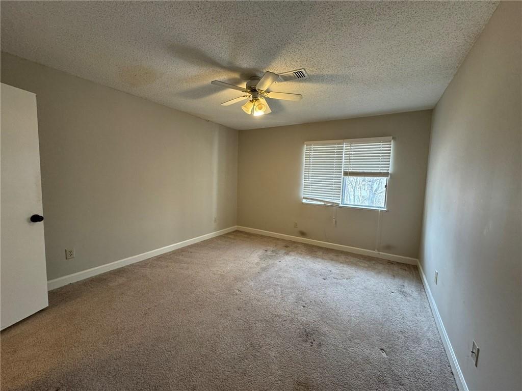 Spare room with a textured ceiling, light carpet, and ceiling fan