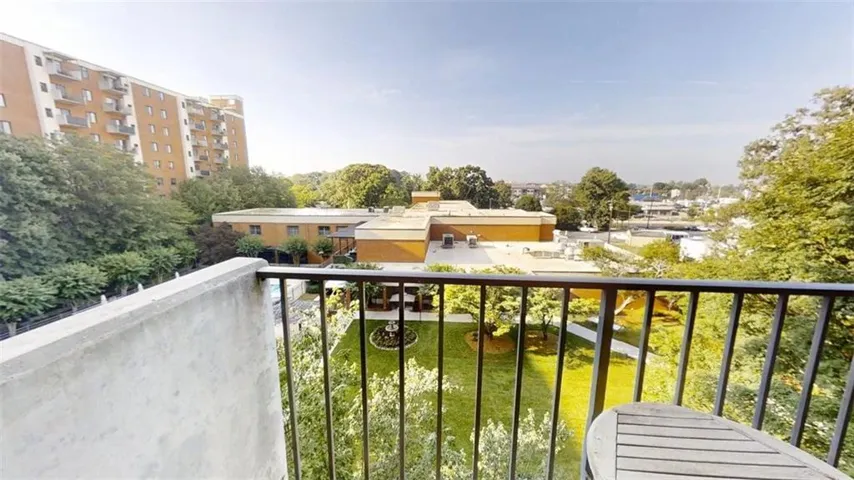 Private balcony with metal railing overlooking a landscaped courtyard and surrounding buildings