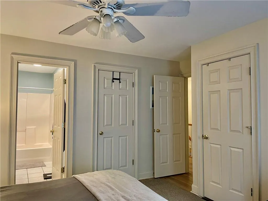 Bedroom featuring ceiling fan, ensuite bathroom, and dark tile flooring