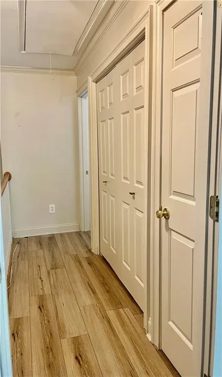 Hall with ornamental molding and light hardwood / wood-style floors