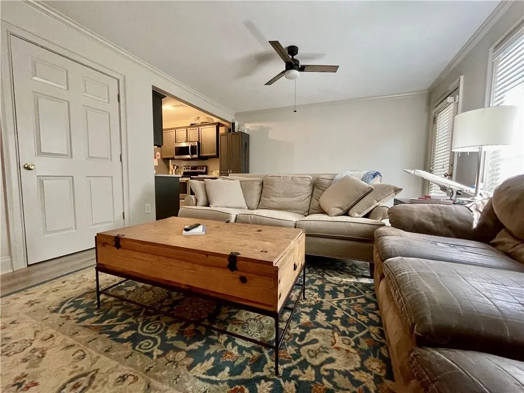 Living room with ornamental molding and ceiling fan