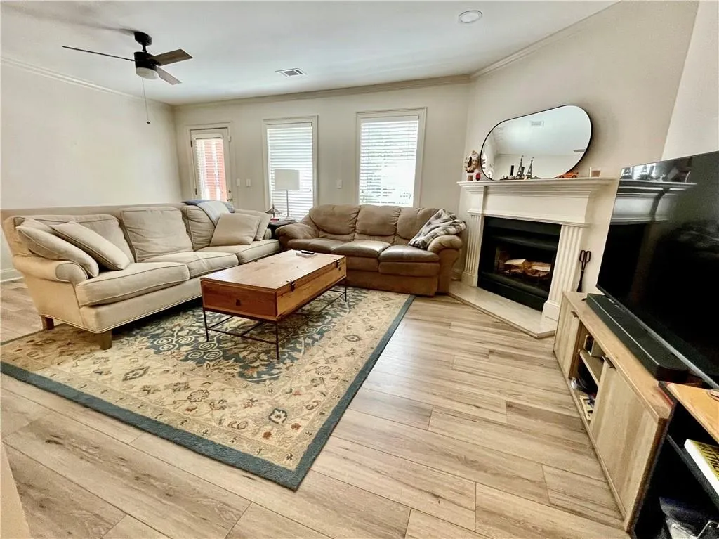 Living room with ornamental molding, light hardwood / wood-style floors, and ceiling fan