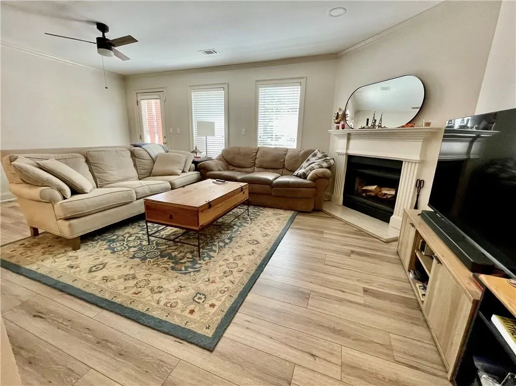 Living room featuring ornamental molding, light hardwood / wood-style flooring, and ceiling fan