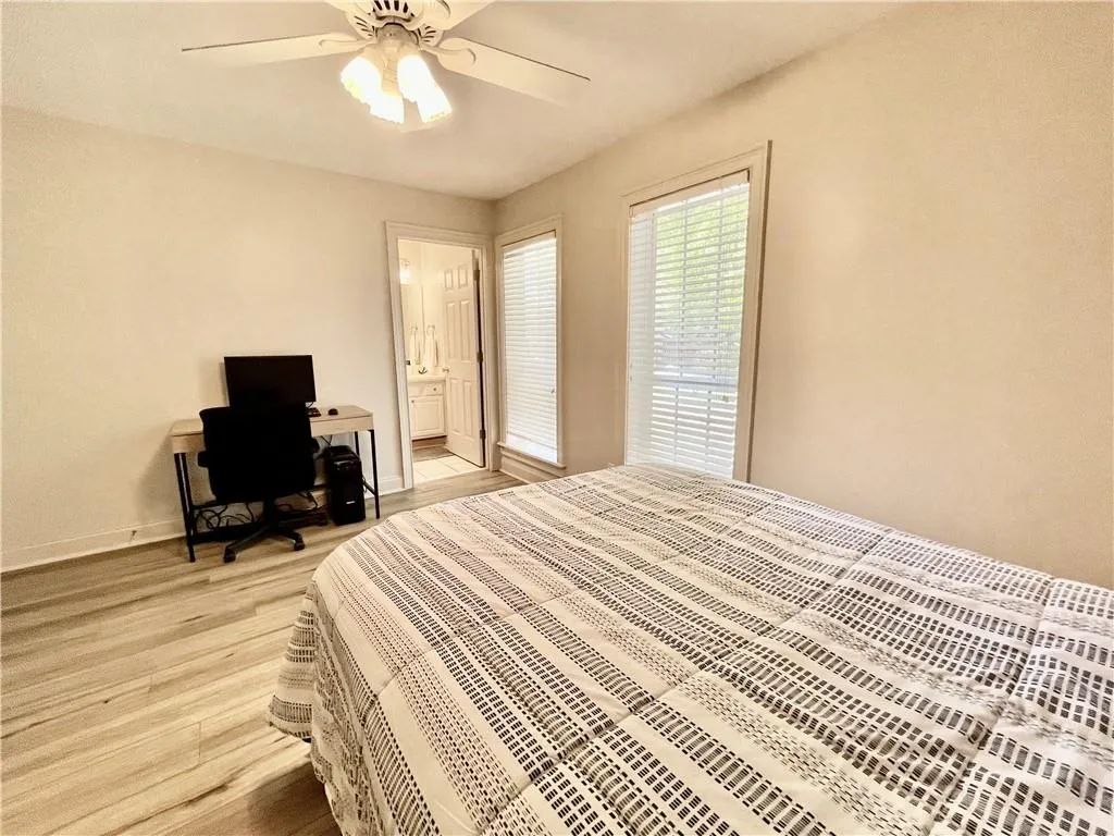 Bedroom featuring ensuite bath, light hardwood / wood-style flooring, and ceiling fan