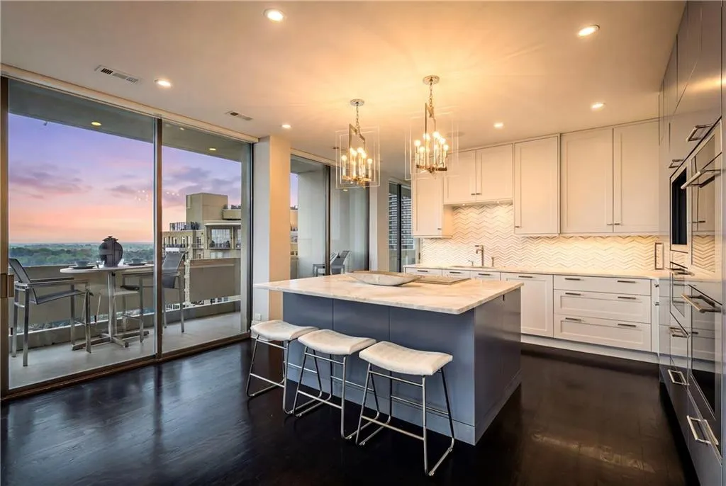 Two tone kitchen with a breakfast bar, a kitchen island, light stone countertops, hanging lights, and dark wood-style flooring