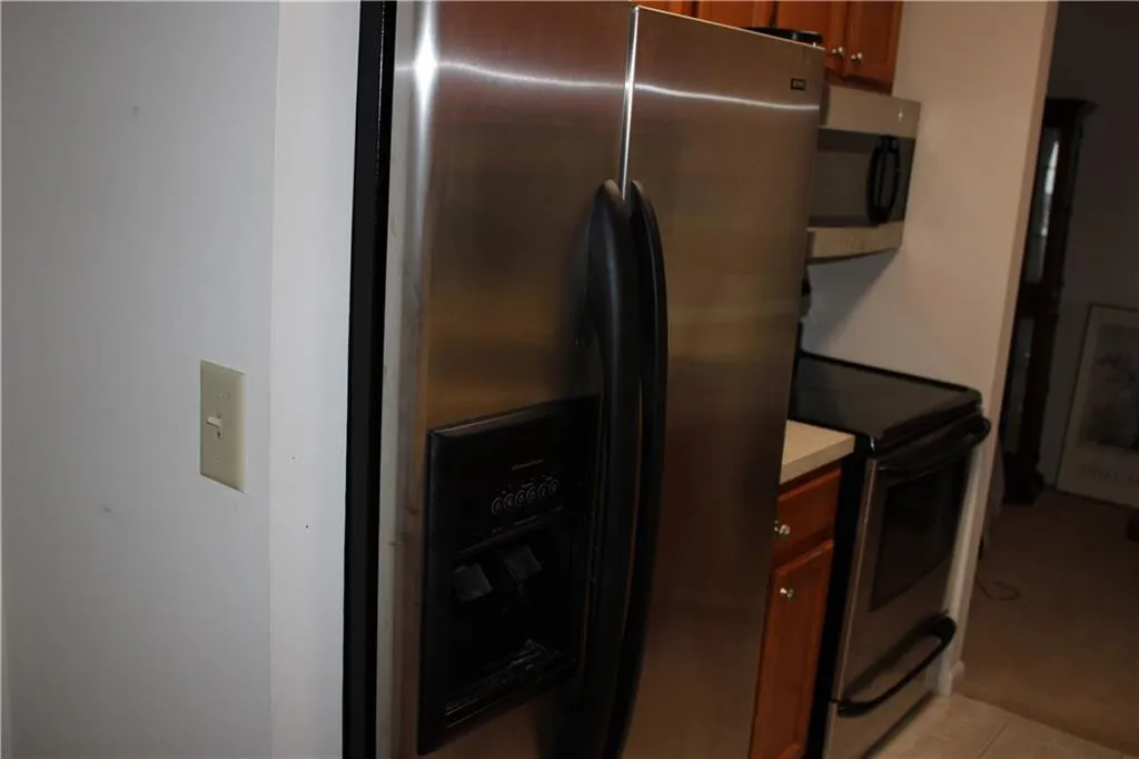 Kitchen with appliances with stainless steel finishes, brown cabinets, light countertops, and light tile patterned floors Kitchen with appliances with stainless steel finishes, brown cabinets, light countertops, and light tile patterned floors