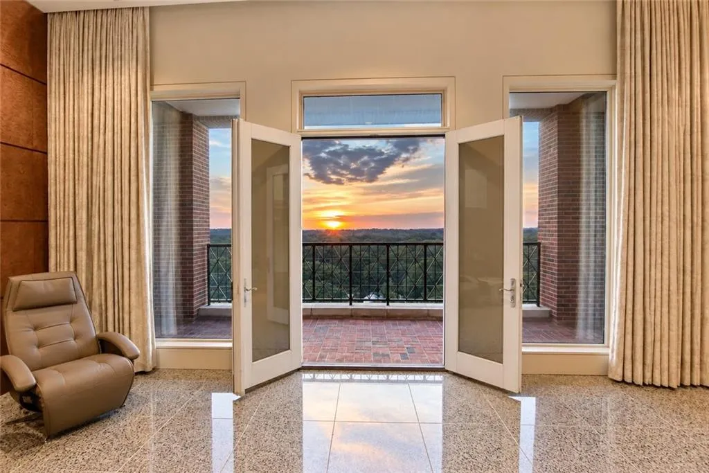 Expansive balcony access through French doors, featuring a brick-patterned floor and black metal railings