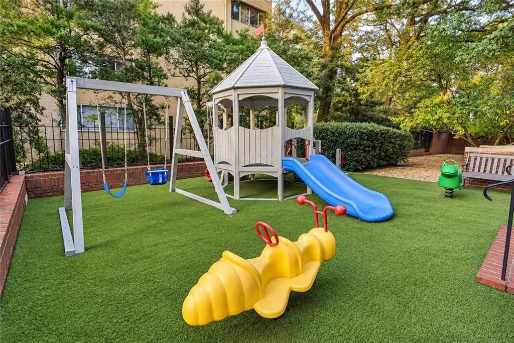 Playground featuring a swing set, slide, and gazebo structure on artificial turf