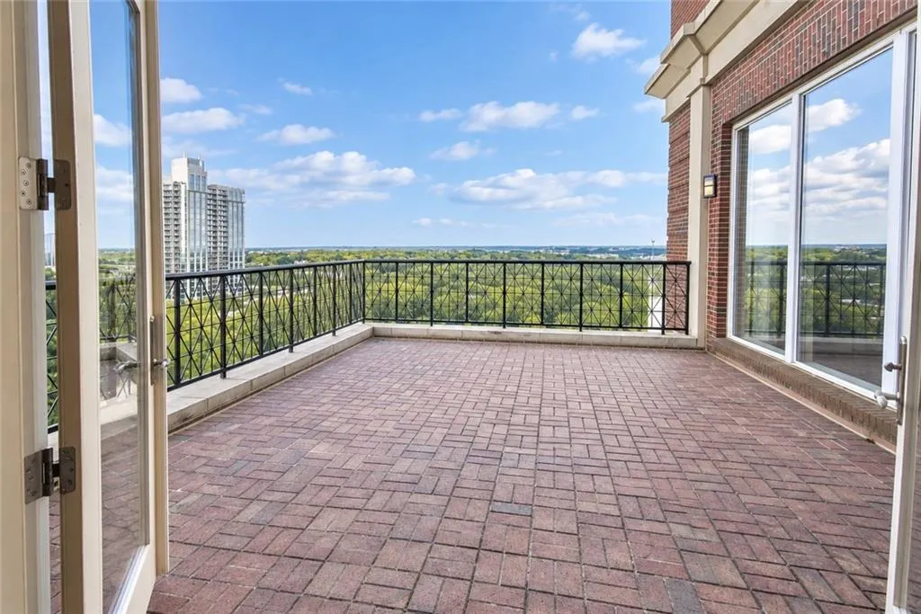 Spacious brick paver terrace with wrought iron railing, expansive glass doors, and a brick exterior
