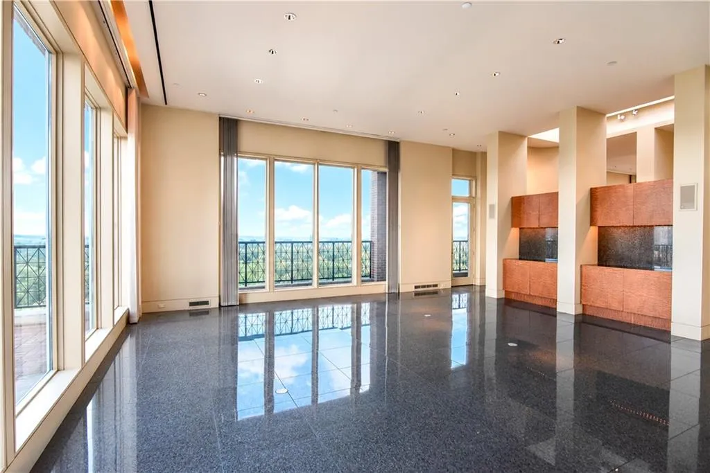 Polished dark stone flooring throughout a spacious room with extensive window walls