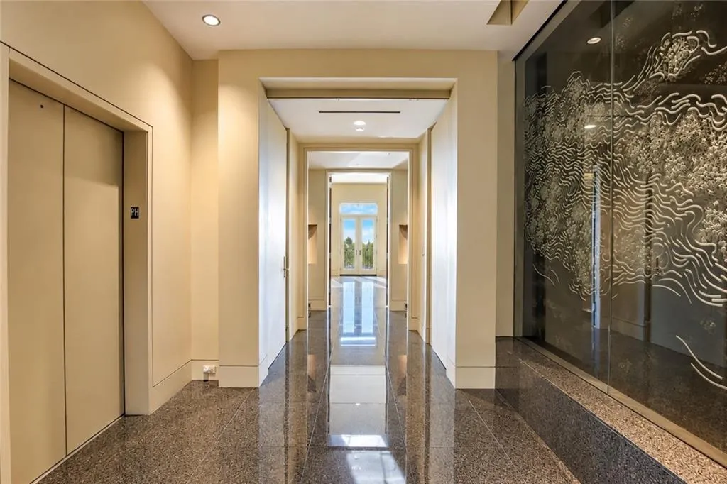 Polished stone flooring, recessed ceiling lighting, and a glass wall with etched detailing