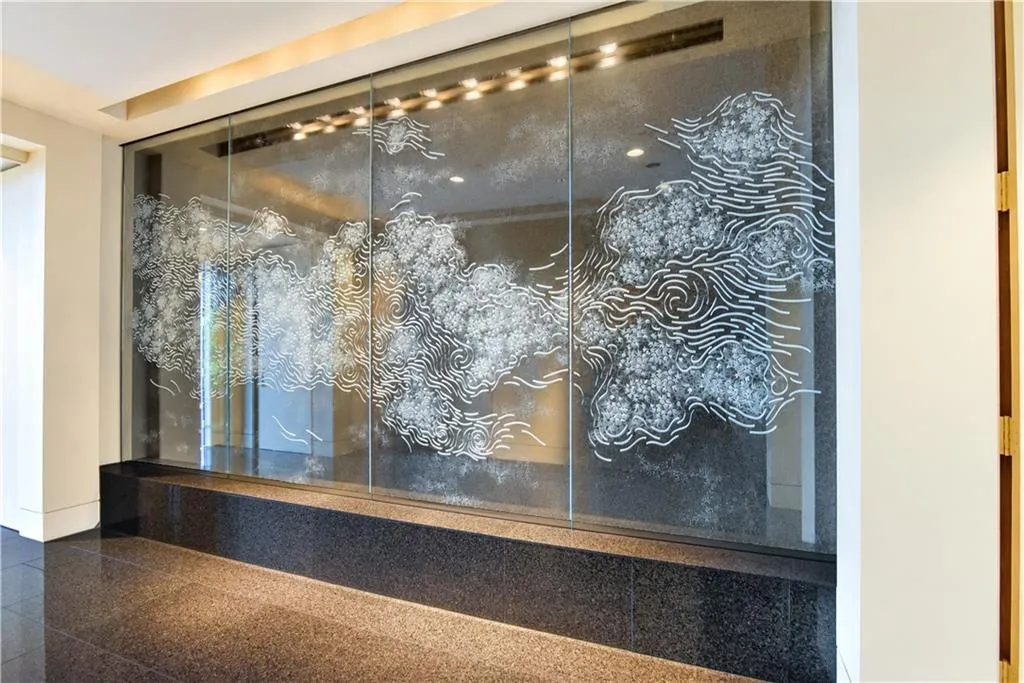 Frosted glass panel featuring intricate design, dark stone flooring, and recessed ceiling lighting