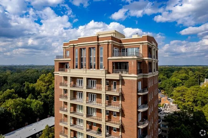 Multi-story high-rise building featuring brick exterior, multiple balconies with metal railings, and extensive window placements