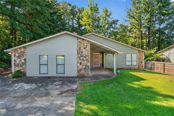Exterior featuring stone accents, horizontal siding, covered entry, and a wood privacy fence