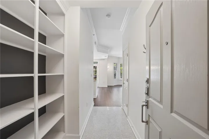 Entryway featuring built-in shelving, a paneled door with brushed nickel hardware, and white mosaic tile flooring