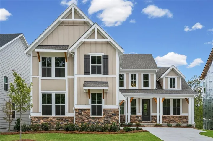 View of front facade with board and batten siding, a front lawn, roof with shingles, a porch, and stone siding